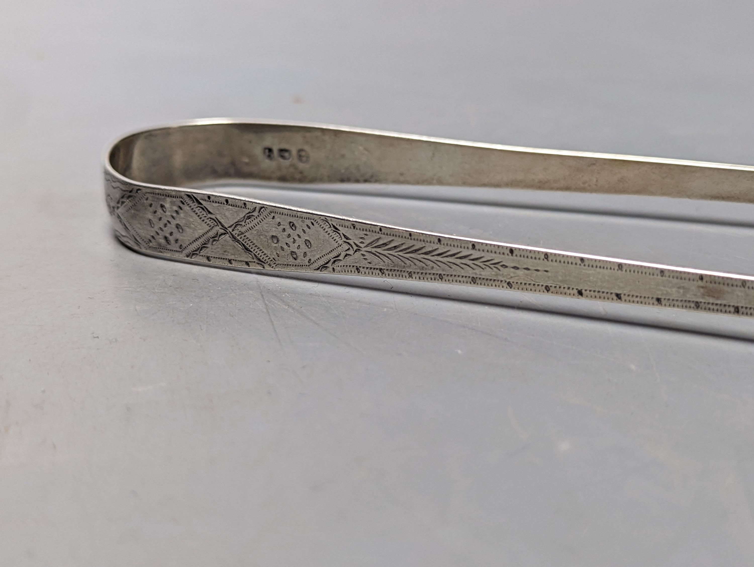 Two pairs of George III bright cut engraved silver sugar tongs and a pair of George IV silver sugar tongs, various dates and makers